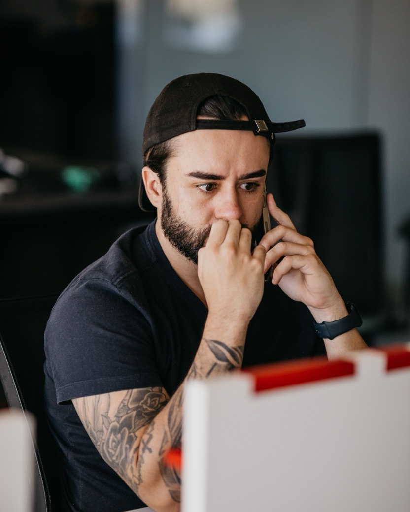 Un homme au téléphone, la main sur la bouche, fixe son écran d’un air inquiet.